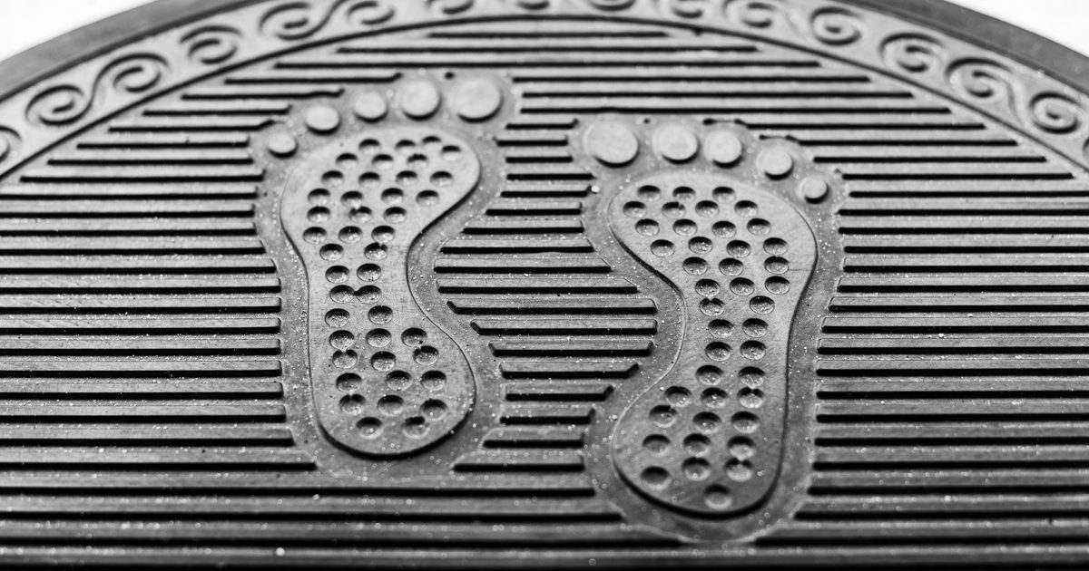 a textured black rubber standing mat with moulded footprints and ribbed grip lines