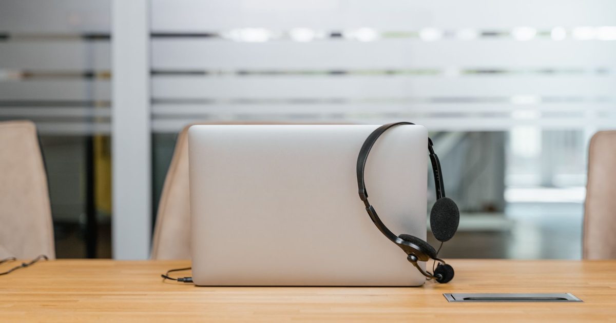 a headset with a boom microphone resting on a laptop on a desk