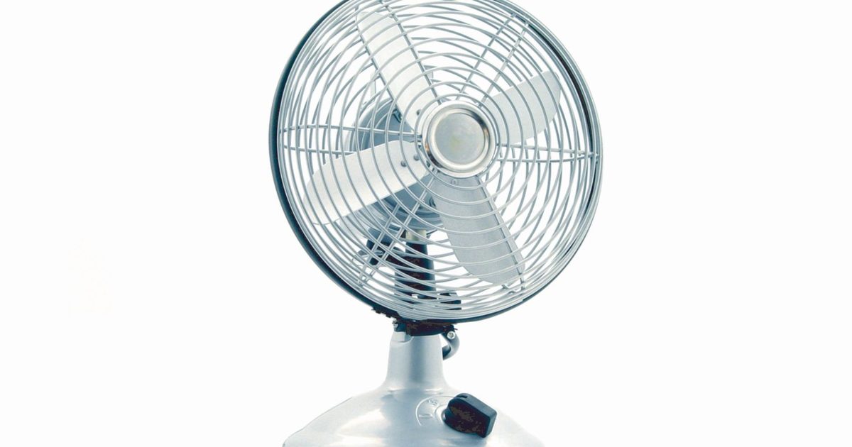 a chrome metal desk fan with a protective cage on a plain background
