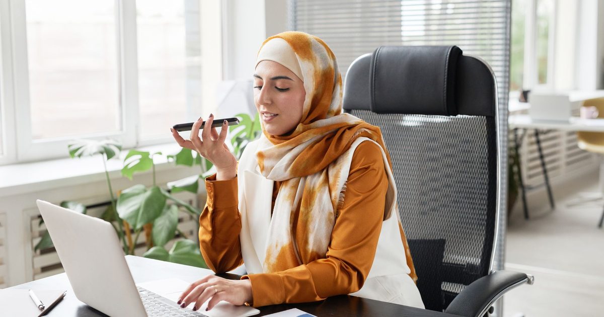 a person on a hands-free call at a bright home-office desk with a laptop