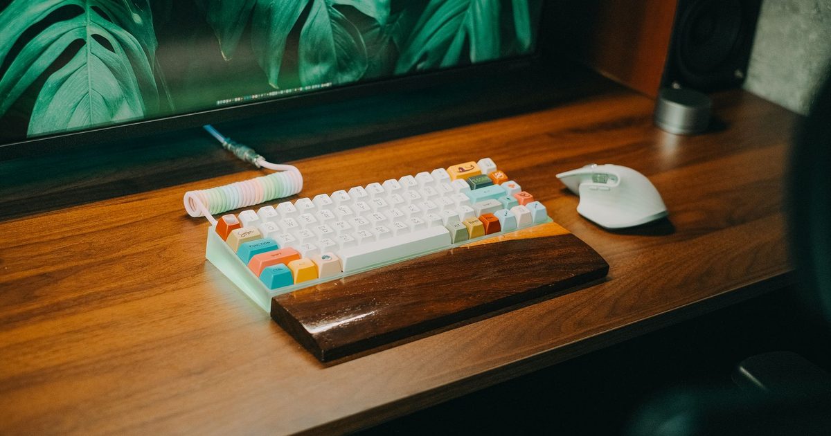 a wooden wrist rest in front of a white mechanical keyboard on a desk