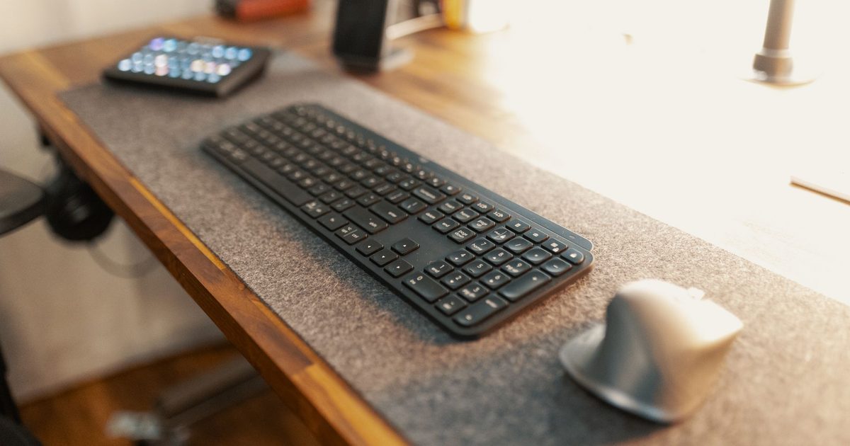 a grey felt desk mat under a keyboard and mouse on a wooden desk