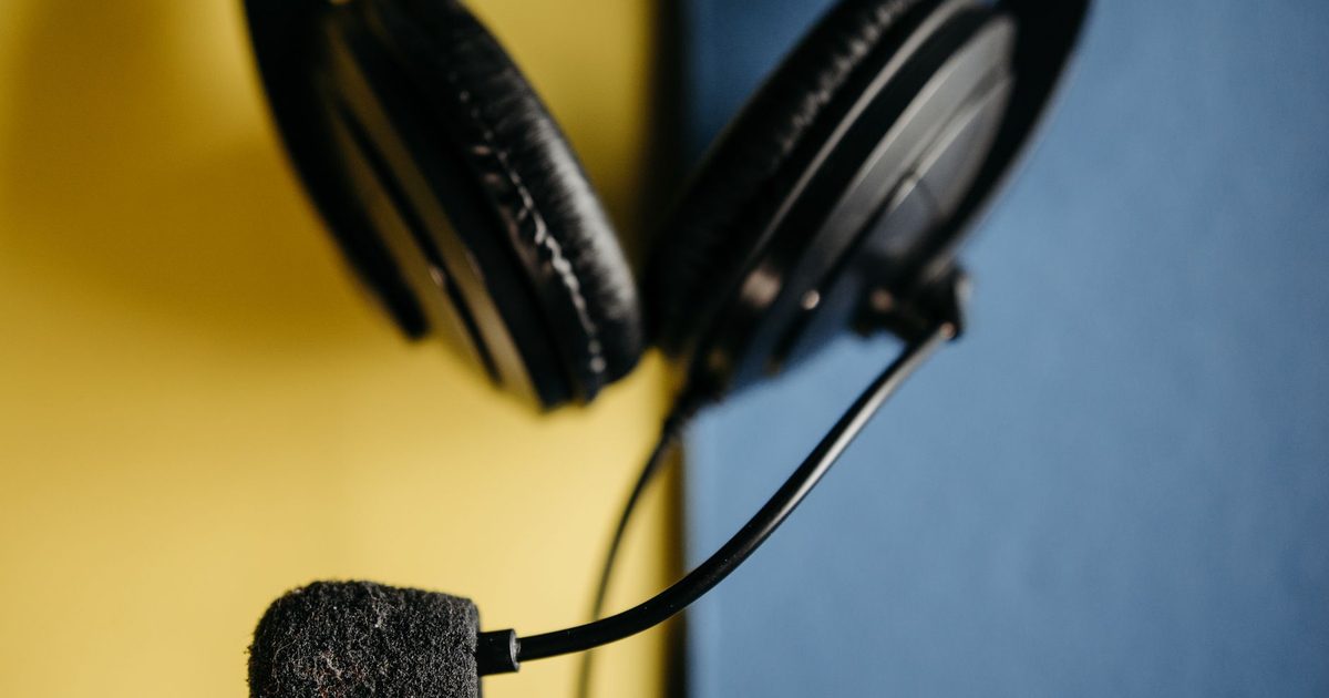 a black over-ear headset with a foam-covered boom microphone on a two-tone background