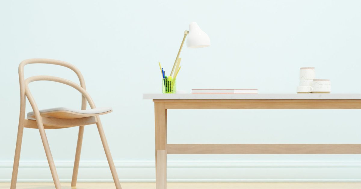 a tidy light wood desk with a lamp and a wooden chair