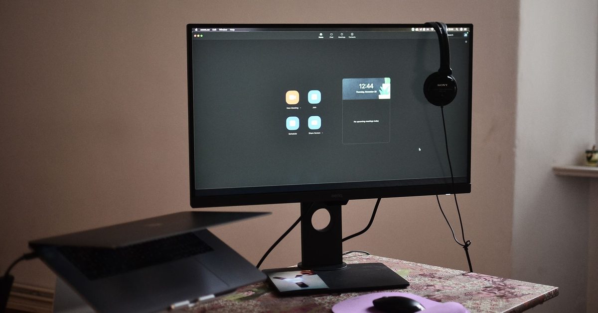 a raised monitor beside a laptop lifted on a stand