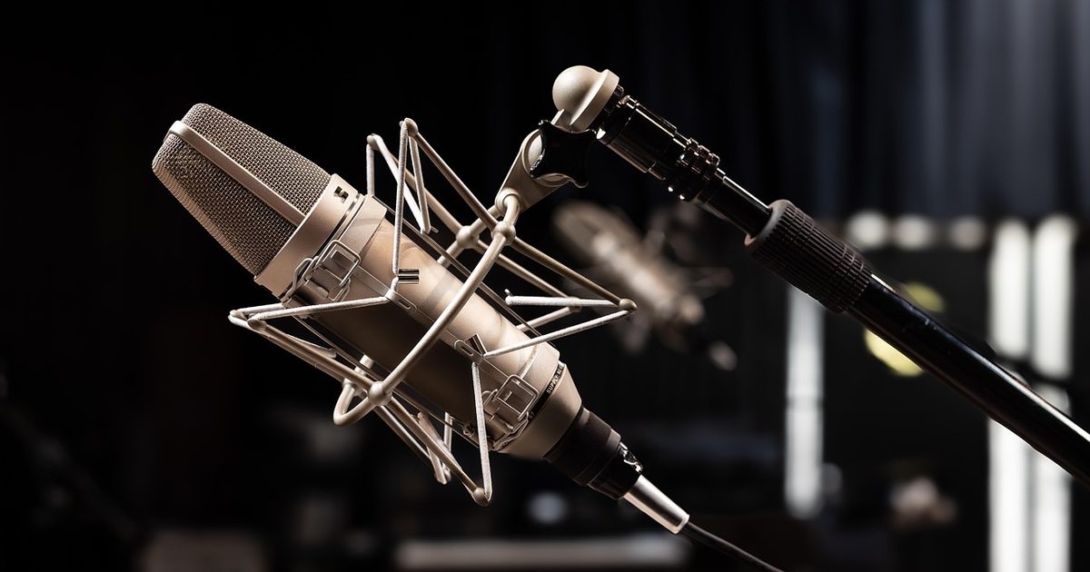 a large condenser microphone suspended in a shock mount against a dark studio background